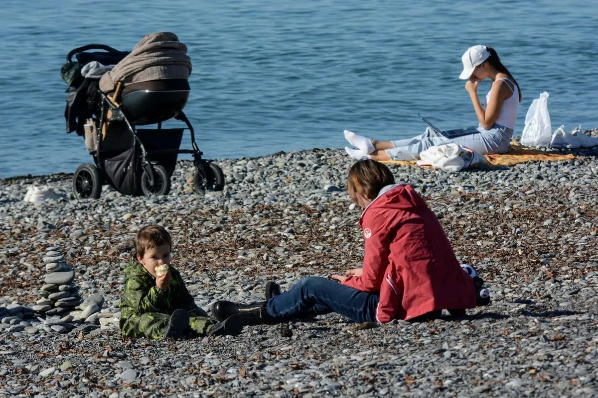 Счастливая семья на пляже в Ялте, ребёнок в коляске стоит рядом